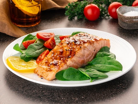 Seared salmon on a plate of greens and tomatoes -- salmon is a great example of a food that can boost your mood